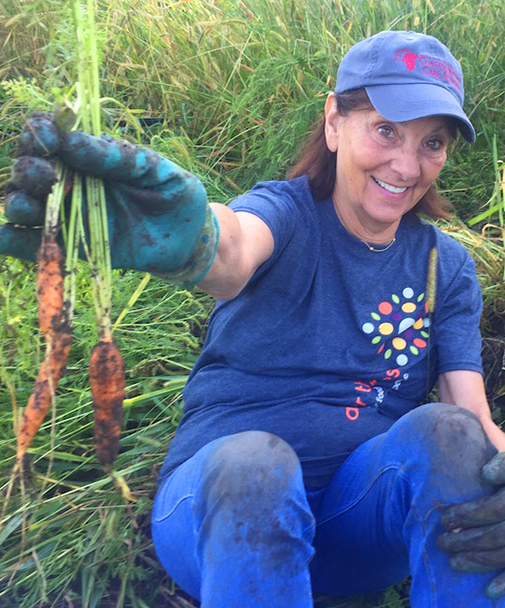 Woman Covered in Dirt Holding Two Carrots